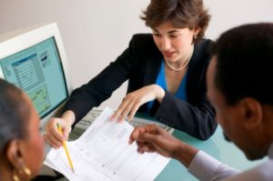 Three people looking at a paper and laptop