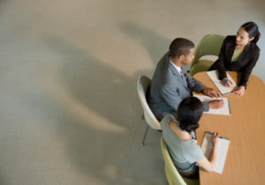 Bird's eye view of two men and a women dressed professionally standing up and talking