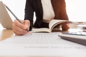 Person leaning over a table writing with a pencil