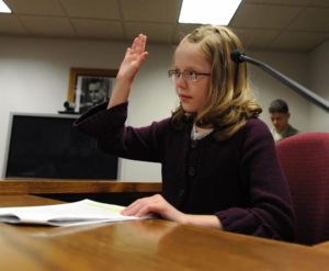 Young girl wearing glasses swearing in