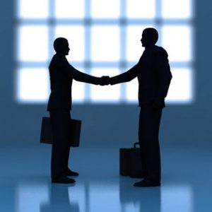 Silhouette of two people shaking hands and holding briefcases