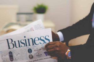 Person holding a newspaper titled "business"