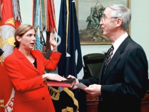 Woman swearing in wearing on a bible with a bright red outfit and a man in a suit