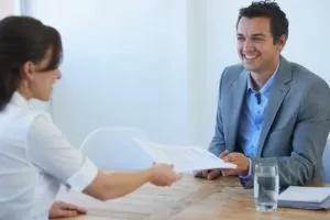 Man handing a paper over to a woman over a table